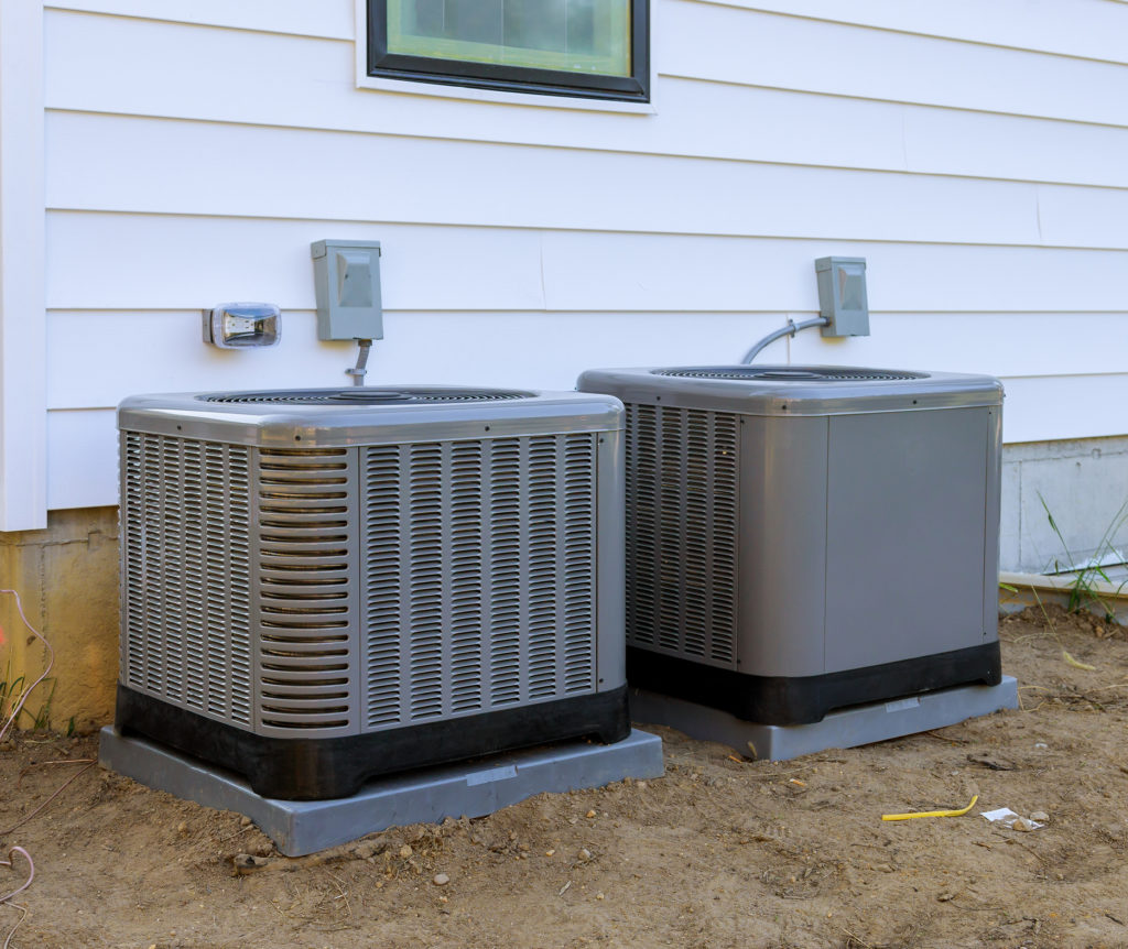 Two outdoor air conditioning units outside a home 